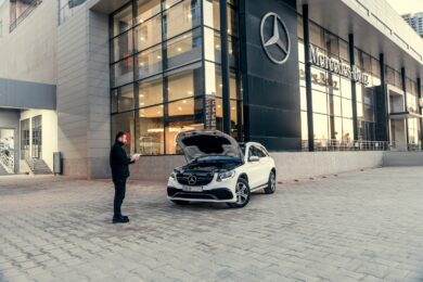 Mand kigger på bil med åben motorhjelm uden for et bilhus