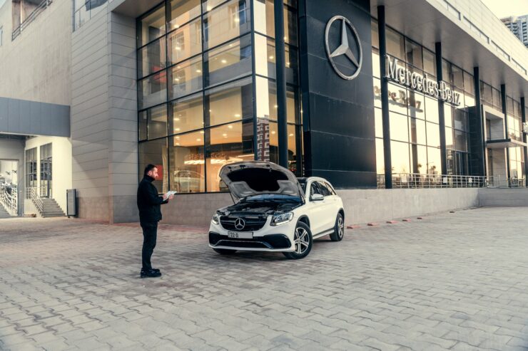 Mand kigger på bil med åben motorhjelm uden for et bilhus